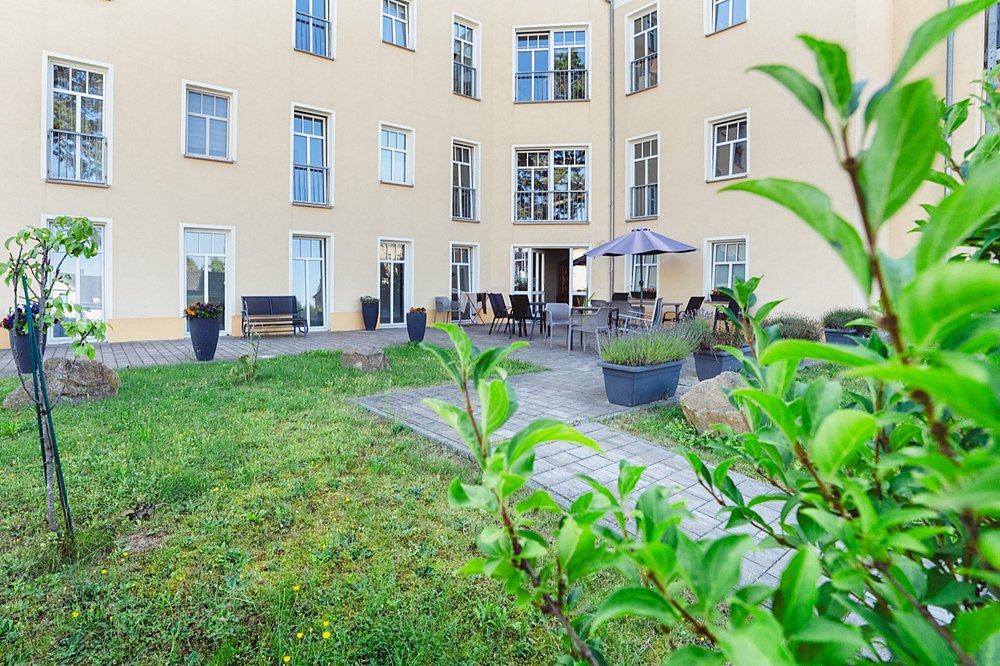 Begrünter Innenhof der Wohngemeinschaft Limbach-Oberfrohna mit Terrasse, Sitzgruppen und Sonnenschirm