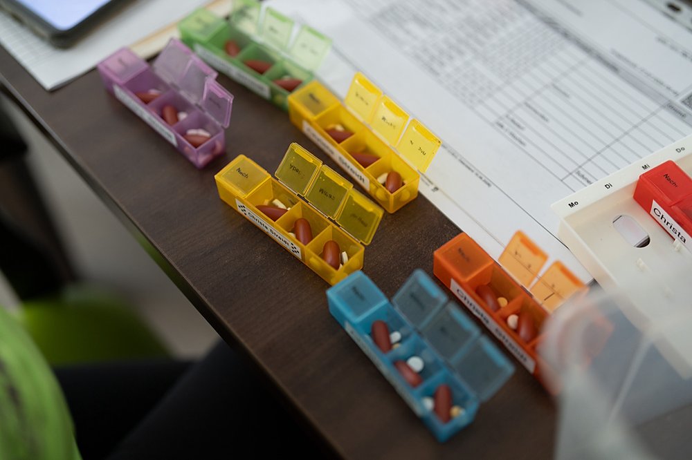 Vorbereitete Medikamentenboxen für die Woche stehen sortiert auf einem Tisch